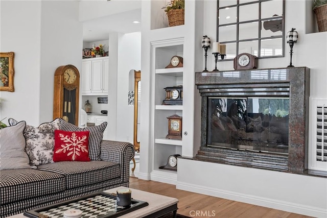 living room with built in features and light hardwood / wood-style flooring