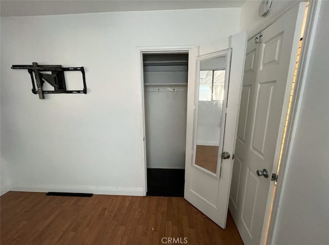 unfurnished bedroom with dark wood-type flooring and a closet