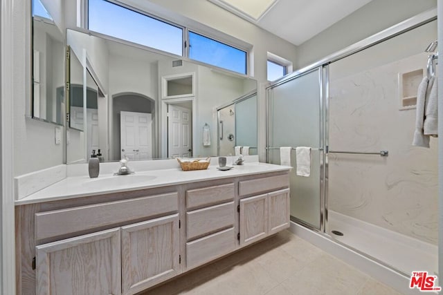 bathroom with tile patterned flooring, vanity, and walk in shower