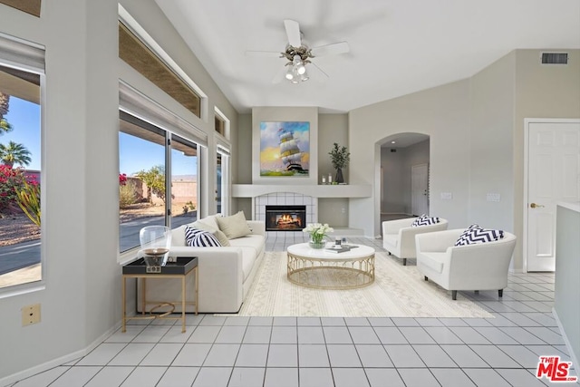 living room featuring light tile patterned floors, ceiling fan, and a tiled fireplace