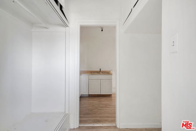 corridor with light hardwood / wood-style flooring and sink