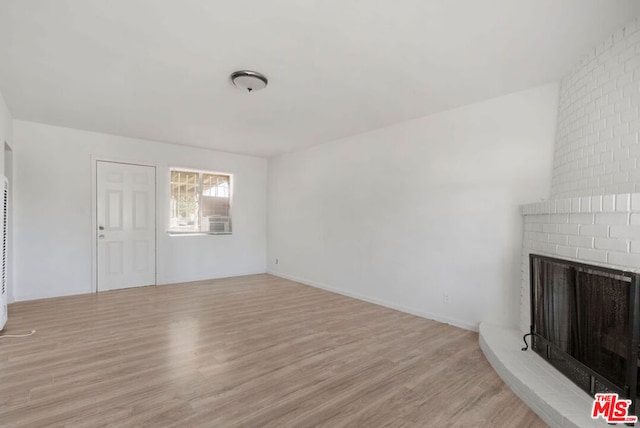 unfurnished living room with light hardwood / wood-style floors and a brick fireplace