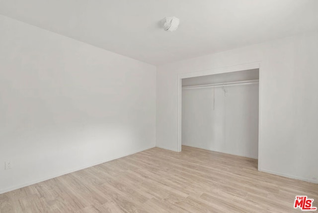 unfurnished bedroom featuring light hardwood / wood-style flooring and a closet