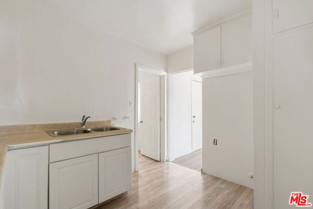 kitchen featuring white cabinets, light wood-type flooring, and sink