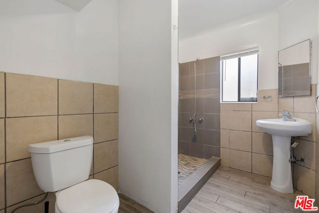 bathroom with walk in shower, toilet, tile walls, and hardwood / wood-style flooring