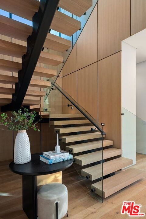 stairway with a towering ceiling and wood-type flooring