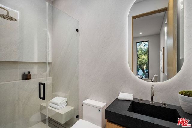 bathroom featuring vanity, a shower with shower door, and toilet