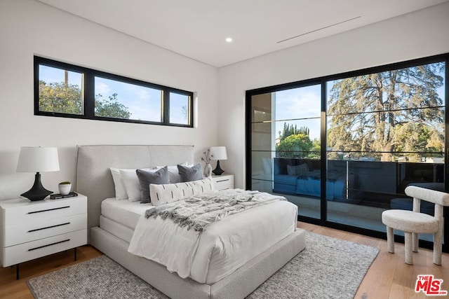 bedroom with access to exterior and hardwood / wood-style flooring