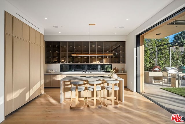 bar featuring backsplash, sink, and light wood-type flooring