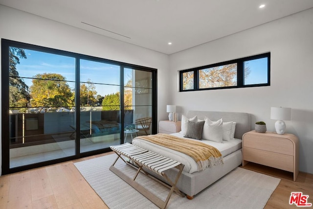 bedroom with hardwood / wood-style floors and access to outside