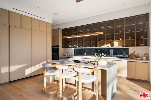 kitchen with decorative backsplash, a kitchen island, and light wood-type flooring