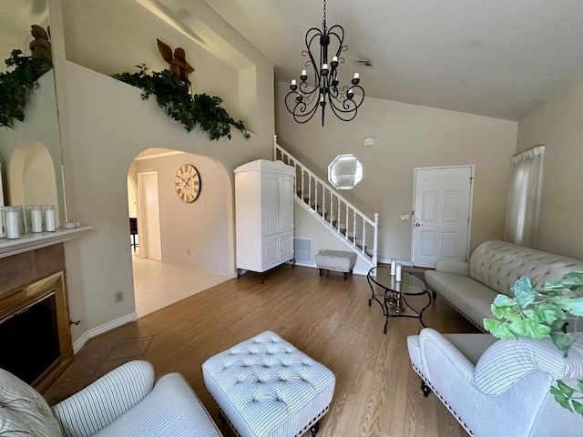 living room with vaulted ceiling, an inviting chandelier, and wood-type flooring