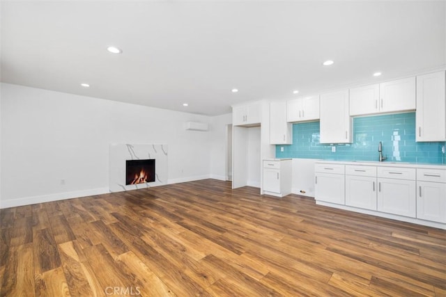 kitchen featuring white cabinets, light hardwood / wood-style floors, a fireplace, and sink