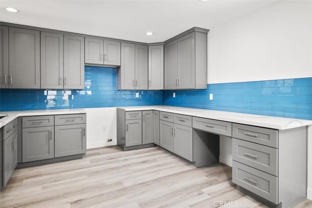 kitchen with backsplash, gray cabinets, and light hardwood / wood-style flooring