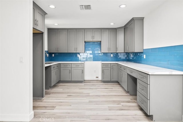 kitchen with gray cabinets, light hardwood / wood-style floors, sink, and tasteful backsplash