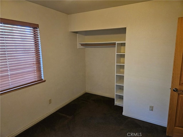 unfurnished bedroom with a closet and dark carpet