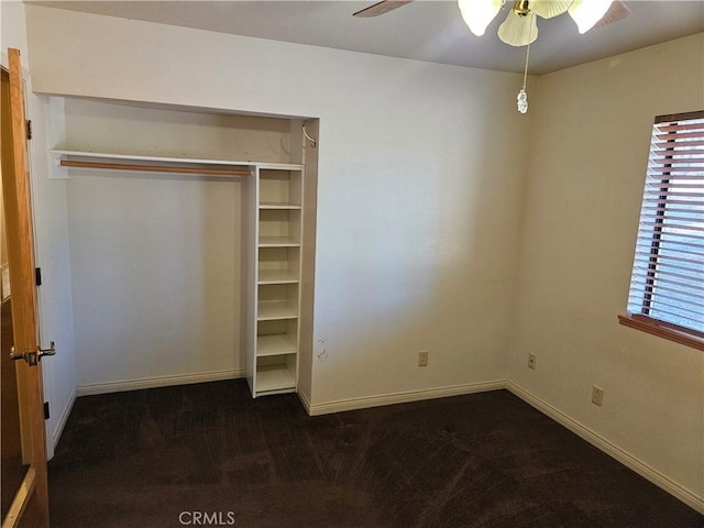 unfurnished bedroom with a closet, dark carpet, and ceiling fan