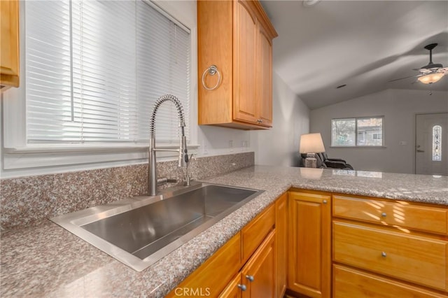 kitchen with kitchen peninsula, ceiling fan, sink, and vaulted ceiling