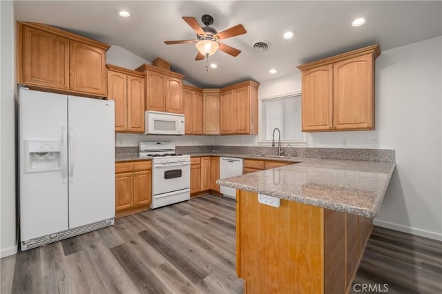 kitchen featuring kitchen peninsula, white appliances, vaulted ceiling, sink, and hardwood / wood-style floors