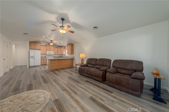 living room featuring ceiling fan, light hardwood / wood-style floors, and vaulted ceiling