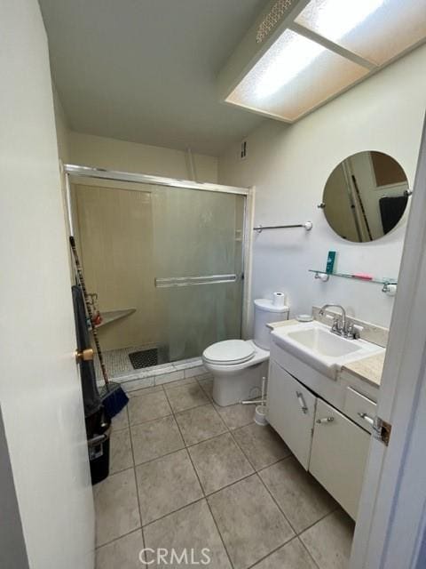 bathroom with tile patterned flooring, vanity, a shower with shower door, and toilet