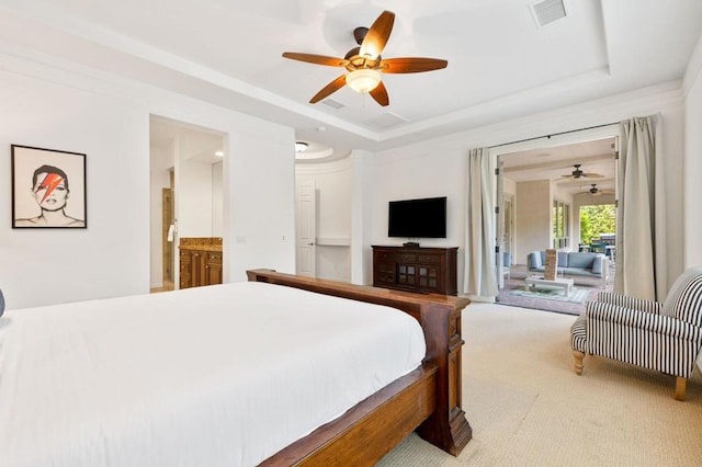 carpeted bedroom featuring a tray ceiling, ensuite bath, and ceiling fan