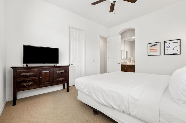 bedroom featuring light carpet, ensuite bath, and ceiling fan