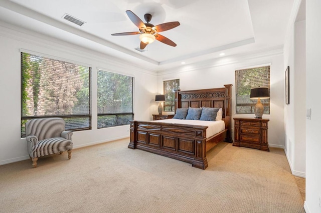 carpeted bedroom featuring a tray ceiling and ceiling fan