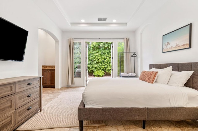 bedroom with access to exterior, connected bathroom, and a tray ceiling