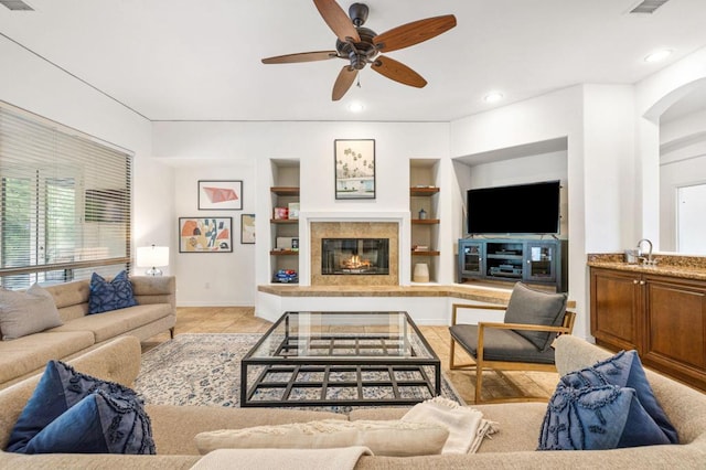 living room with sink, built in shelves, ceiling fan, light tile patterned floors, and a fireplace