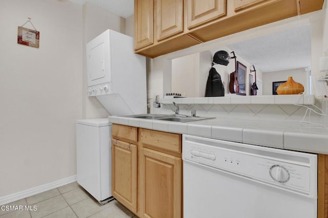 clothes washing area featuring light tile patterned flooring, sink, and stacked washer and clothes dryer