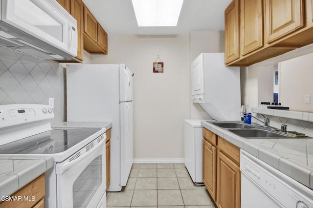 kitchen featuring tile counters, white appliances, sink, and a skylight