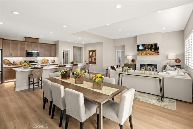 dining room with a fireplace, light hardwood / wood-style flooring, and sink