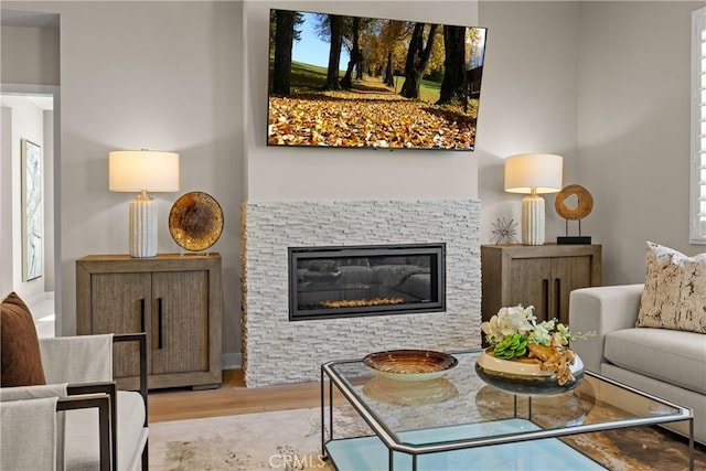 sitting room with light hardwood / wood-style floors and a stone fireplace