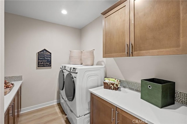 clothes washing area featuring washer and dryer, cabinets, and light wood-type flooring