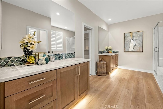 bathroom featuring decorative backsplash, hardwood / wood-style floors, vanity, and a shower with door