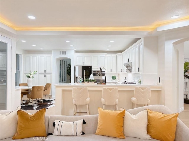 kitchen featuring white cabinets, appliances with stainless steel finishes, a breakfast bar, and decorative backsplash