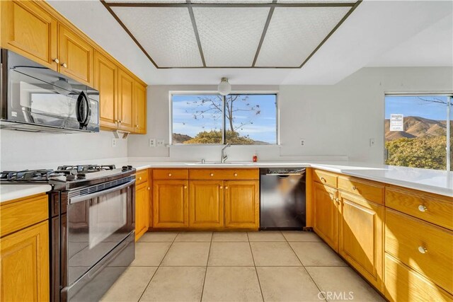 kitchen with a healthy amount of sunlight, sink, light tile patterned flooring, and black appliances