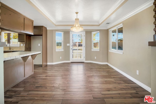 interior space featuring a tray ceiling, tile countertops, dark hardwood / wood-style floors, and a notable chandelier