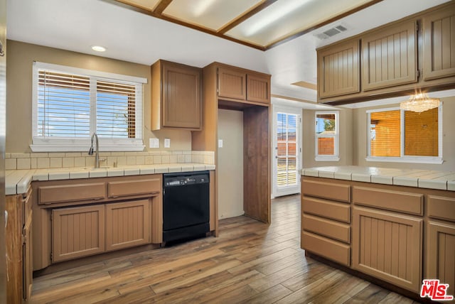 kitchen featuring dishwasher, a notable chandelier, backsplash, tile countertops, and hardwood / wood-style floors