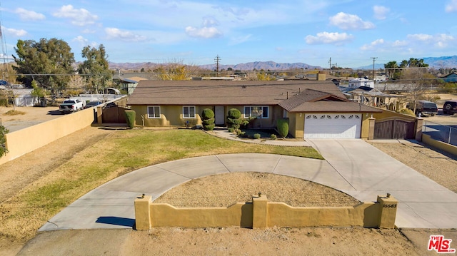 ranch-style home with a mountain view, a front lawn, and a garage