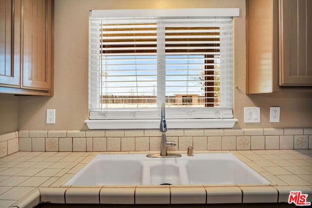 interior details featuring tile countertops and sink