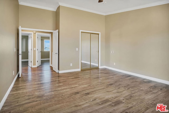 unfurnished bedroom featuring a closet, ceiling fan, crown molding, and hardwood / wood-style flooring