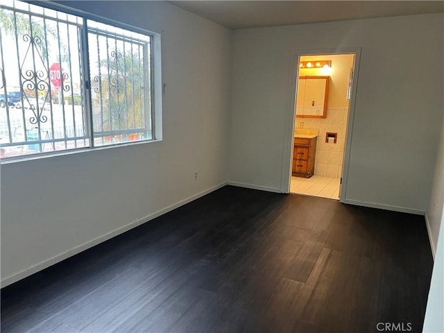 spare room featuring a healthy amount of sunlight and dark hardwood / wood-style flooring