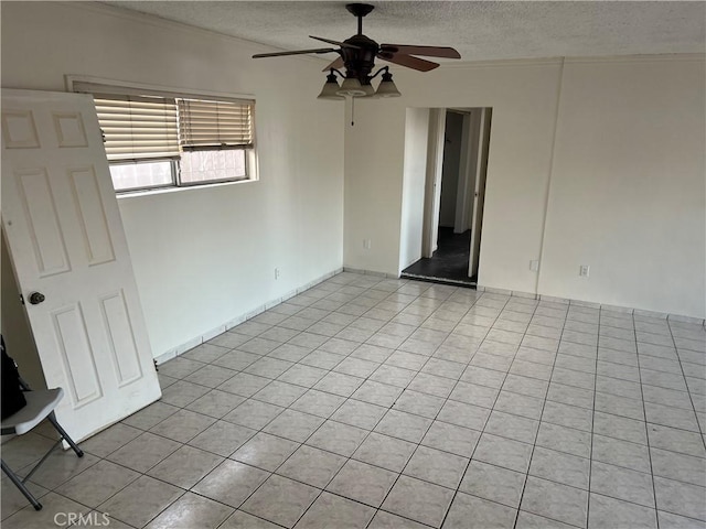 empty room featuring ceiling fan, light tile patterned flooring, and a textured ceiling