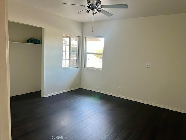 empty room with ceiling fan and dark wood-type flooring