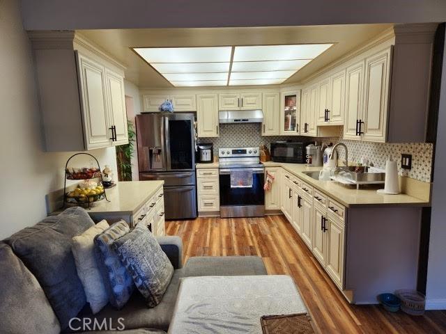 kitchen featuring stainless steel appliances, light hardwood / wood-style flooring, tasteful backsplash, and sink