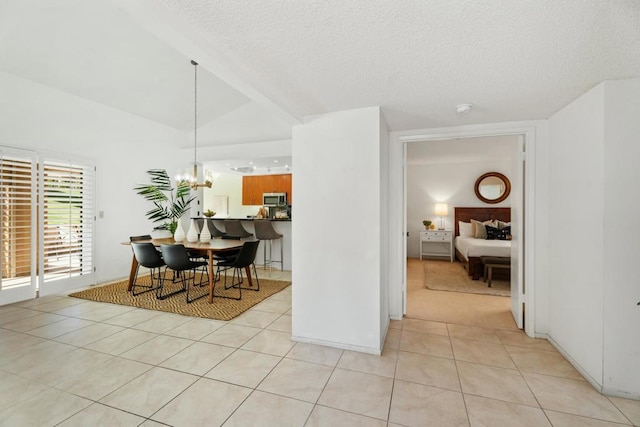 dining space with light tile patterned floors, vaulted ceiling, a textured ceiling, and an inviting chandelier