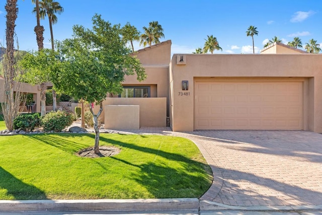 pueblo-style home with a garage and a front yard