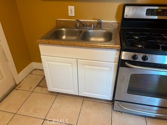 kitchen featuring white cabinets, light tile patterned floors, sink, and gas range